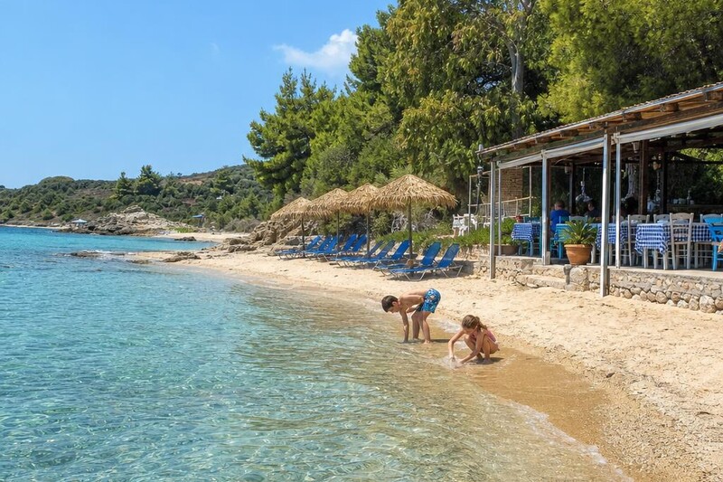 Clear turquoise water and sandy beach at Halkidiki, Greece, with a small family-run taverna and umbrellas