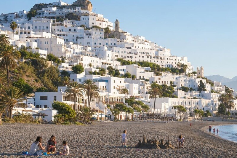 Whitewashed hill town of Mojacar in Almeria, Spain, with a wide sandy beach below in the foreground